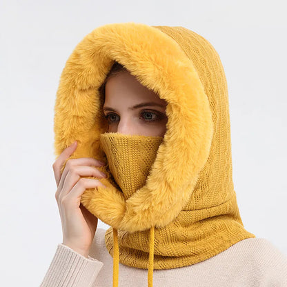 Person wearing a mustard yellow knitted cowl with fur trim on a light gray background