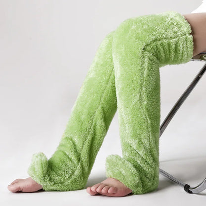 Green fuzzy leg warmers worn by a person on a white background