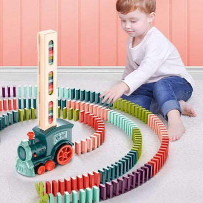 Child playing with a colorful train and domino set on a light-colored floor.