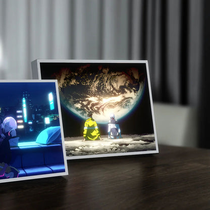 Two framed artworks on a table with a curtain in the background