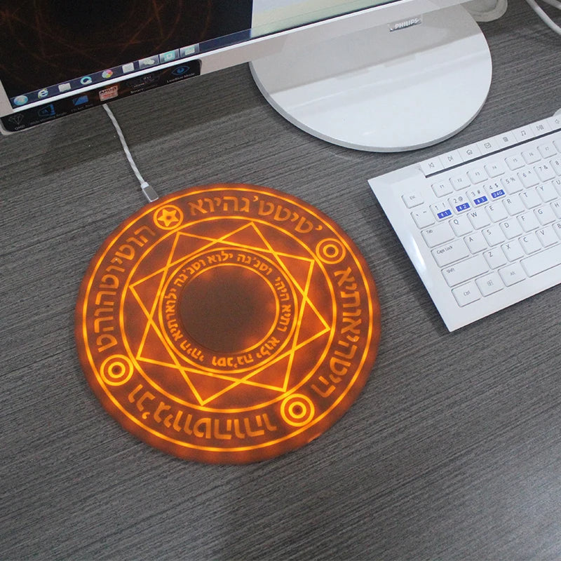 Decorative mouse pad with glowing circular design on a desk with computer equipment.