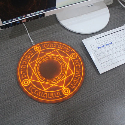 Decorative mouse pad with glowing circular design on a desk with computer equipment.