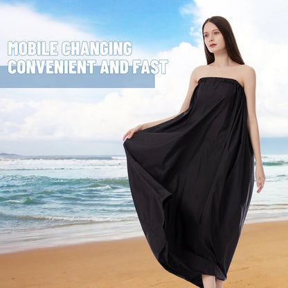 Woman holding a black strapless dress on a beach with text overlay.