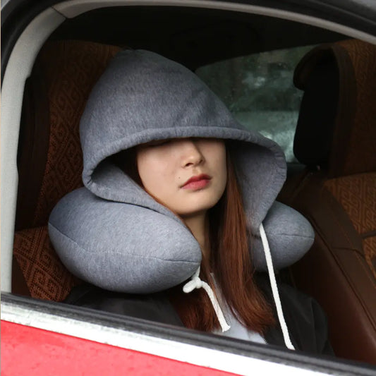 Person wearing a gray hooded travel pillow inside a car.