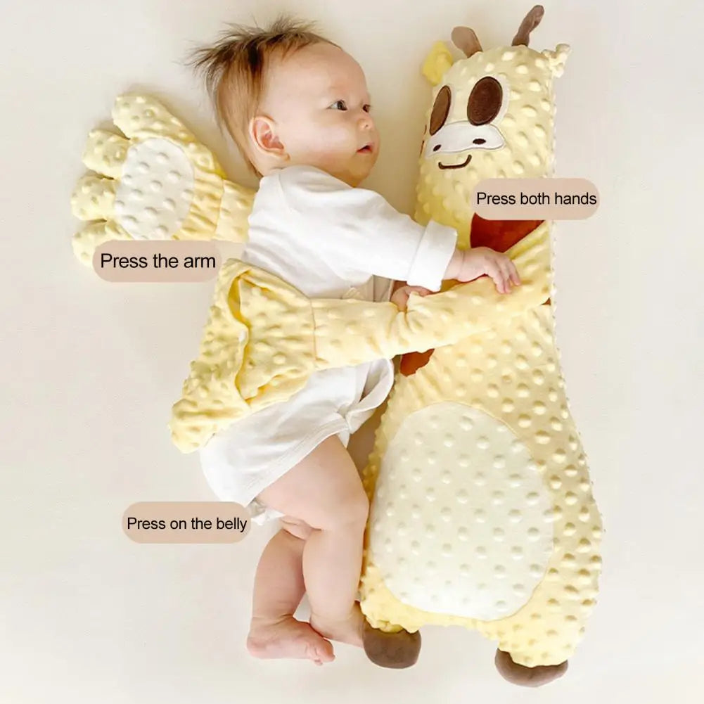 Baby lying on a yellow plush toy with instructions to press different parts of the toy.