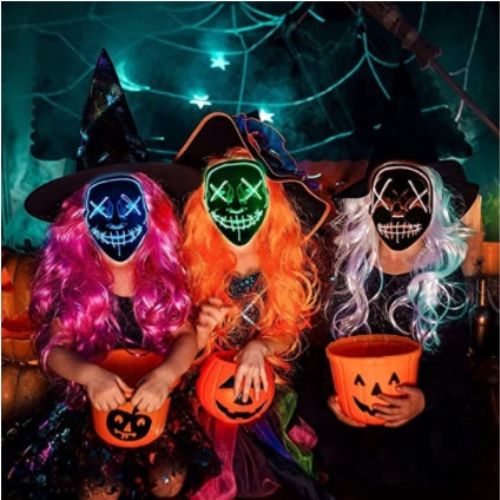 Three people in Halloween costumes with glowing face masks and pumpkin buckets.