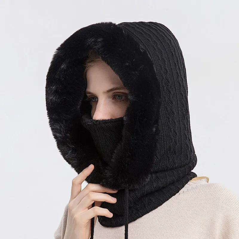 Person wearing a black knitted hood with fur trim on a white background