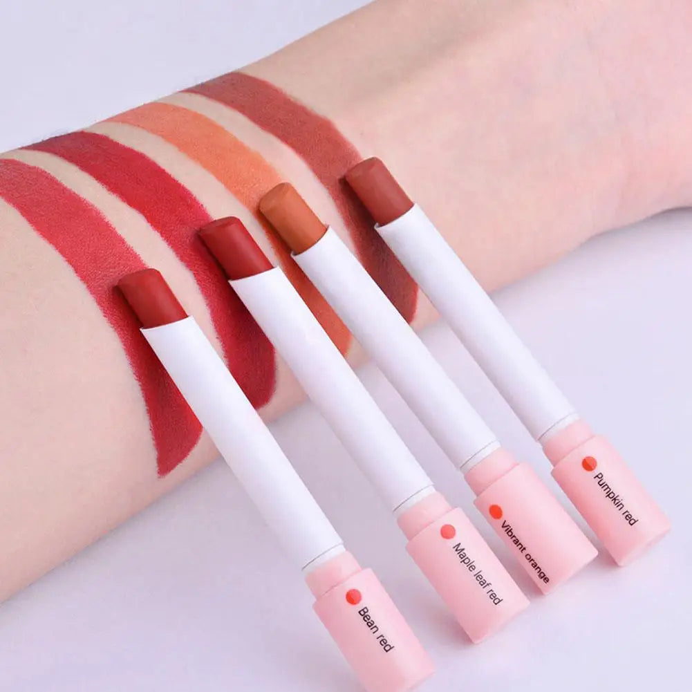 Four lip glosses with pink and white packaging on a light background