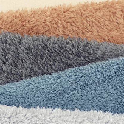 Stack of textured bath mats in brown, gray, blue, and white.