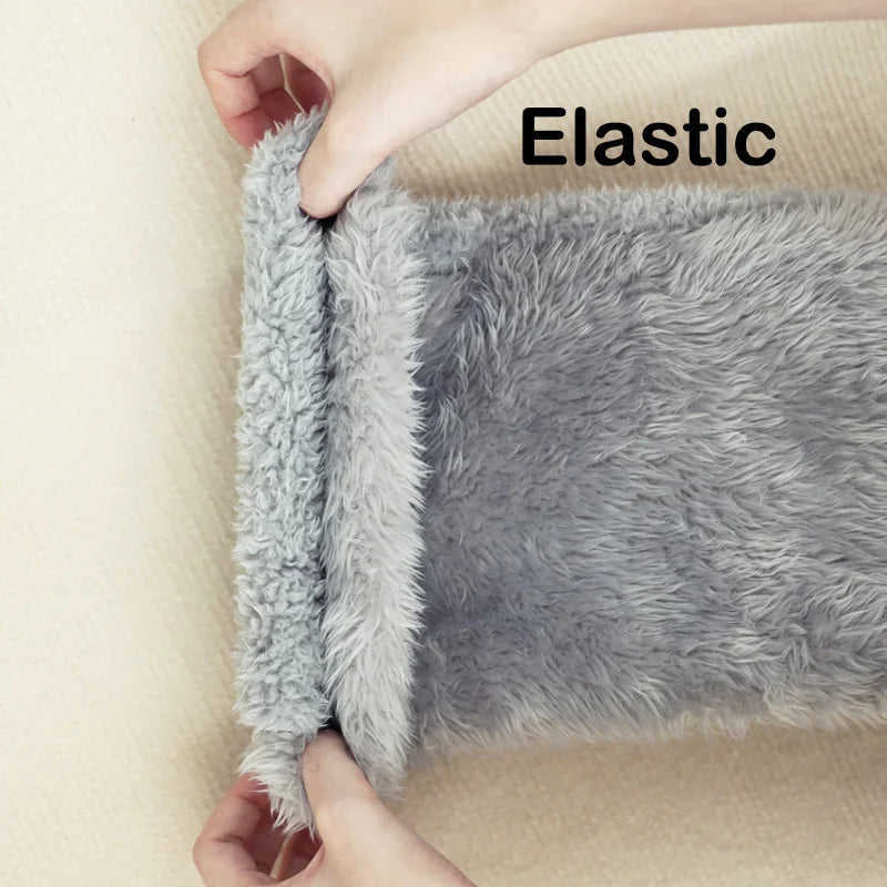 Gray fluffy rug with elastic edge being stretched by hands on a beige background
