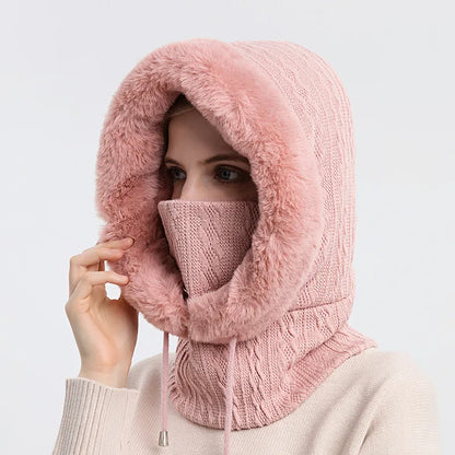 Person wearing a pink knitted hood and mask on a light gray background