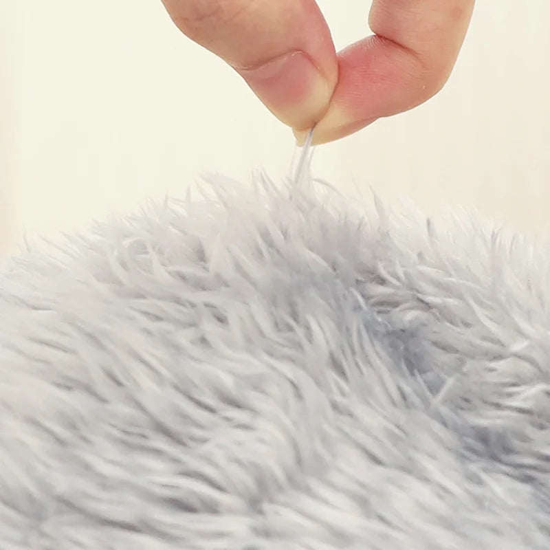 Close-up of a hand holding a white thread over a fluffy white surface.